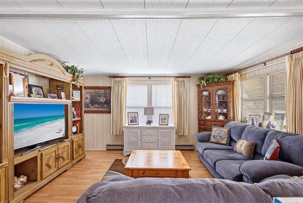 A living room features wood-paneled walls, a large entertainment center, a blue sofa, and wood flooring — 4109 12TH STREET E, ELLENTON, FL
