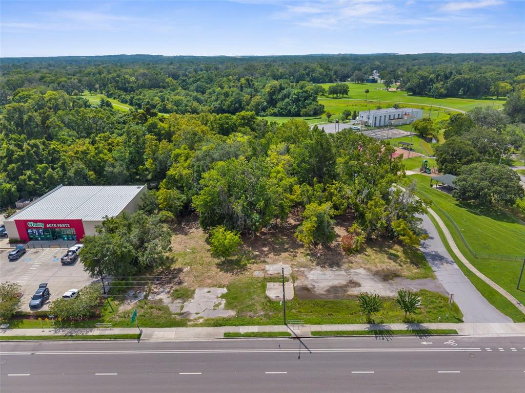 An aerial view shows a vacant lot with concrete foundations next to an auto parts store — 802 S BROAD STREET, BROOKSVILLE, FL
