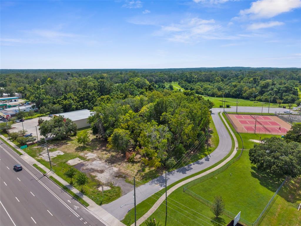 An aerial view shows a vacant lot with concrete pads next to a road and tennis courts — 802 S BROAD STREET, BROOKSVILLE, FL