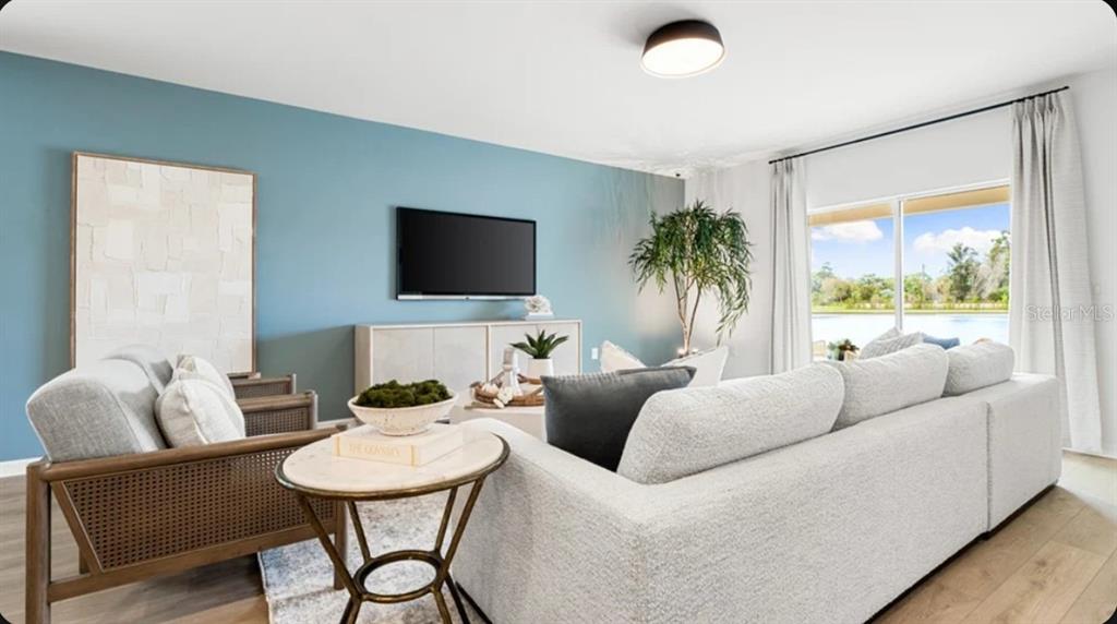 A living room features a blue accent wall, a white sofa, and a large window — 7417 FIELDSTONE DRIVE, GROVELAND, FL