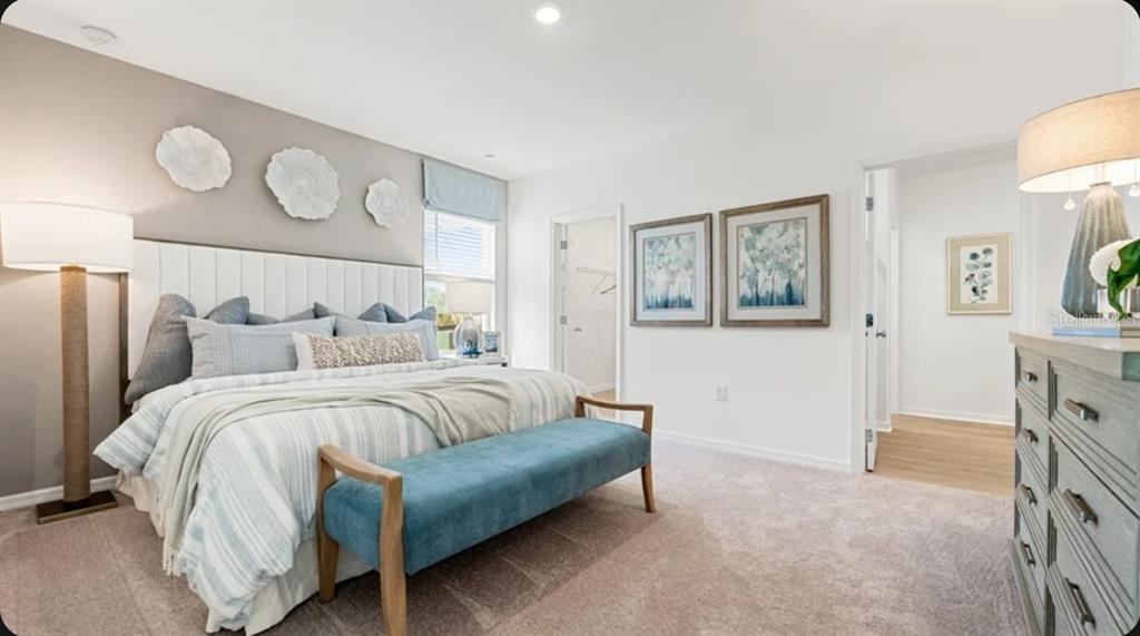 A bedroom features a bed with a blue bench, a dresser, and wall-mounted floral decor — 7417 FIELDSTONE DRIVE, GROVELAND, FL