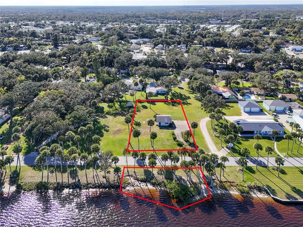 An aerial view shows a house on a large lot with waterfront access — 5040 RIVERSIDE DRIVE, PORT ORANGE, FL