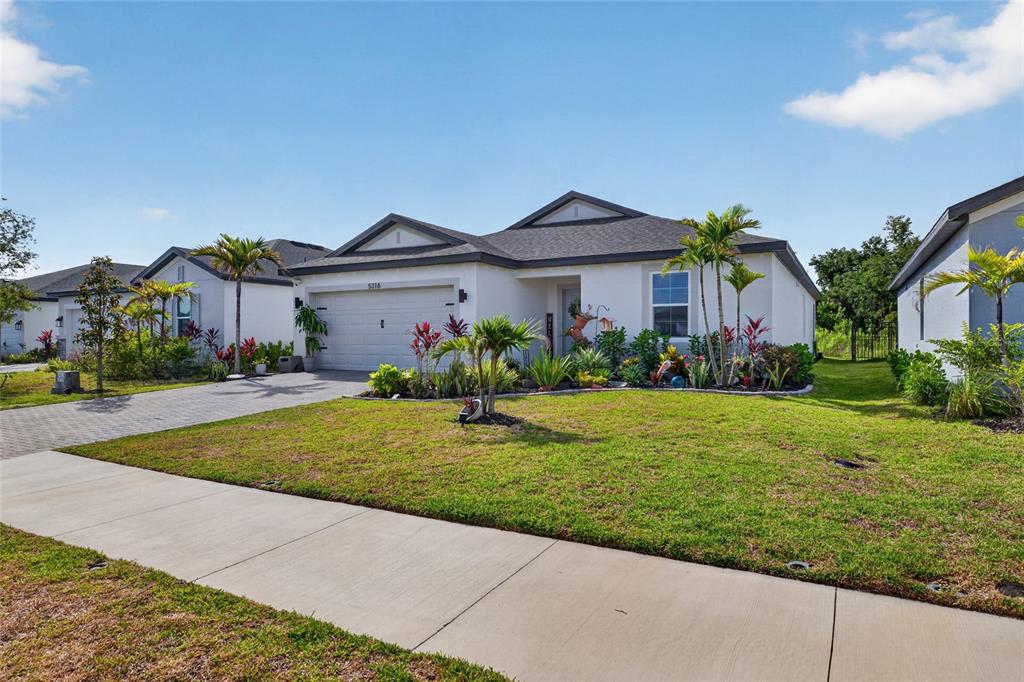 A single-story suburban house features a two-car garage, a paved driveway, and landscaped front yard — 5316 PATANO LOOP, PALMETTO, FL