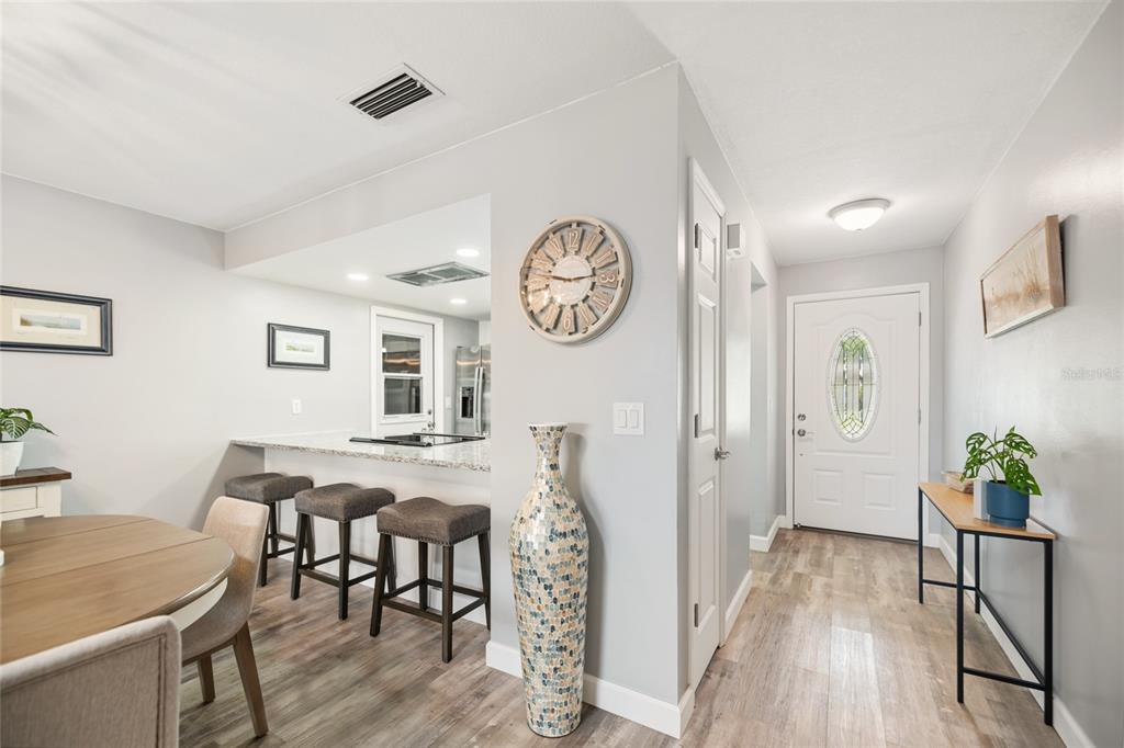 A dining area with a breakfast bar and entryway featuring light wood-look flooring — 38 LAUREL OAKS CIRCLE, ORMOND BEACH, FL