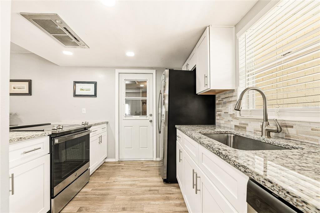 A kitchen features white cabinets, granite countertops, stainless steel appliances, and a glass-paneled exterior door — 38 LAUREL OAKS CIRCLE, ORMOND BEACH, FL
