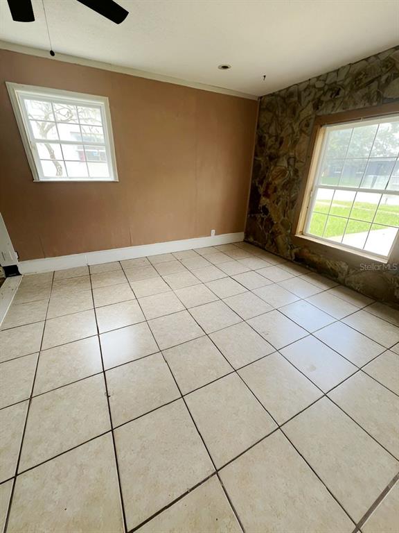 A room with light-colored tile flooring, beige walls, and a stone accent wall — 8118 ESPERANZA STREET, ORLANDO, FL