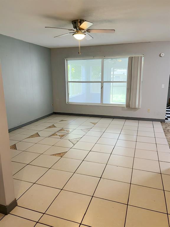 A room with light-colored tile flooring, a ceiling fan, and a large window — 8118 ESPERANZA STREET, ORLANDO, FL