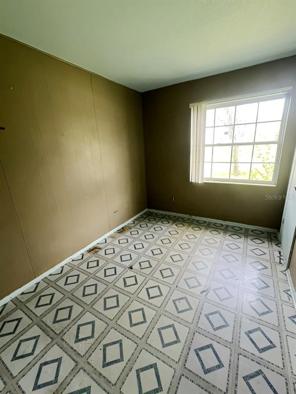 An empty room features brown paneled walls and a white floor with a diamond pattern — 8118 ESPERANZA STREET, ORLANDO, FL