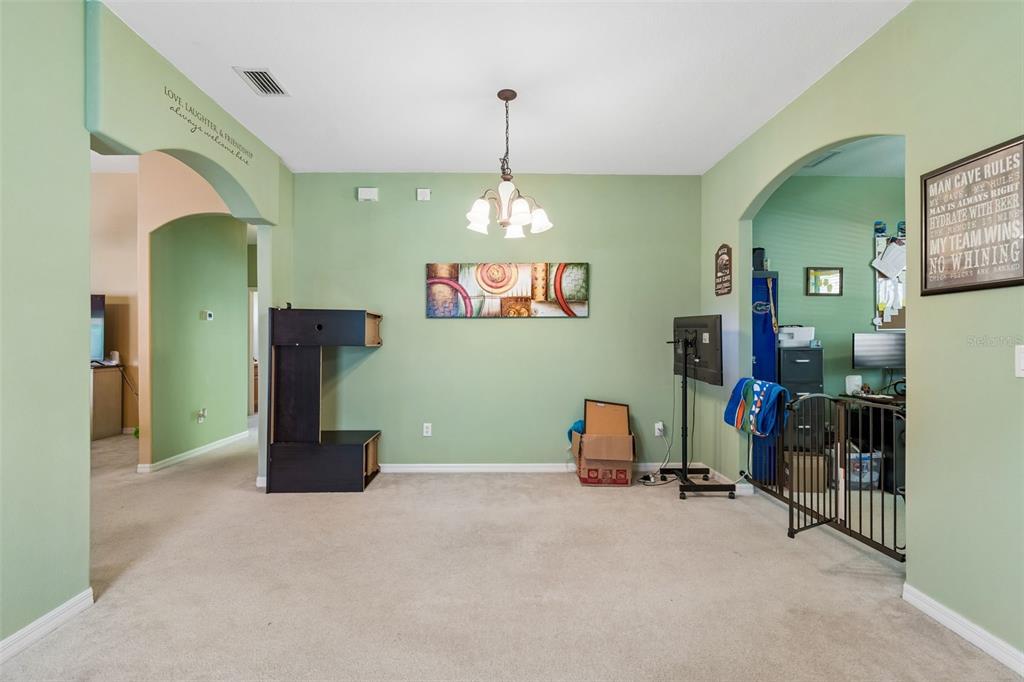 A dining area with light green walls, carpeted flooring, and a central chandelier — 4017 LANGDRUM DRIVE, WESLEY CHAPEL, FL