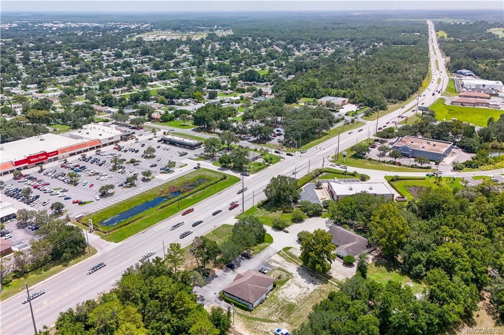 An aerial view shows a commercial shopping center with a parking lot near a highway — 3628 N LECANTO HIGHWAY, BEVERLY HILLS, FL