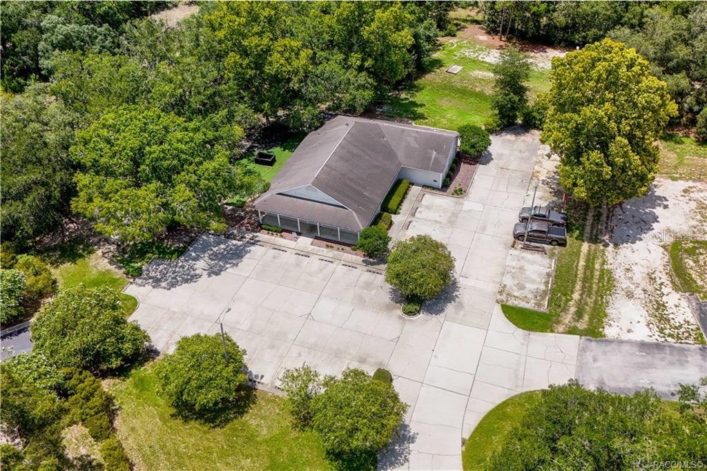 An aerial view shows a single-story building with a large concrete parking lot and trees — 3628 N LECANTO HIGHWAY, BEVERLY HILLS, FL