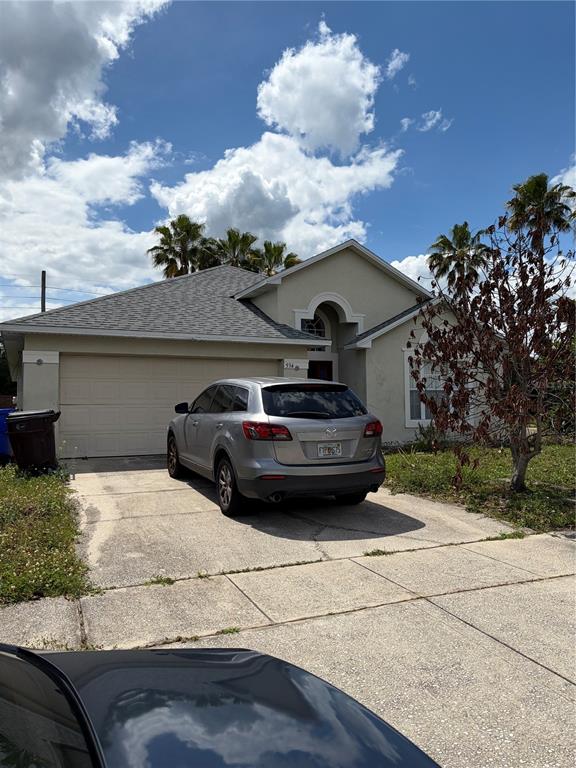 A silver SUV is parked in the driveway of a single-story house with palm trees — 534 EAGLE POINTE S, KISSIMMEE, FL