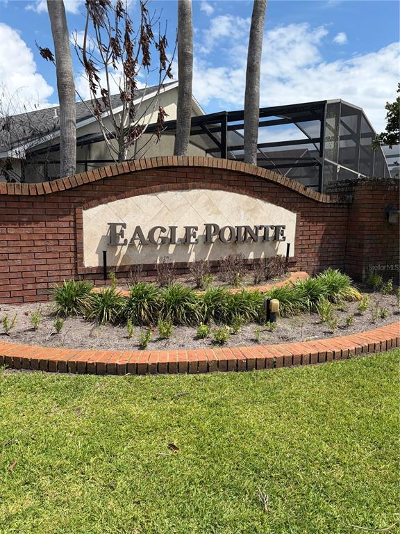 A brick entrance sign for Eagle Pointe stands in front of a house with a pool cage — 534 EAGLE POINTE S, KISSIMMEE, FL