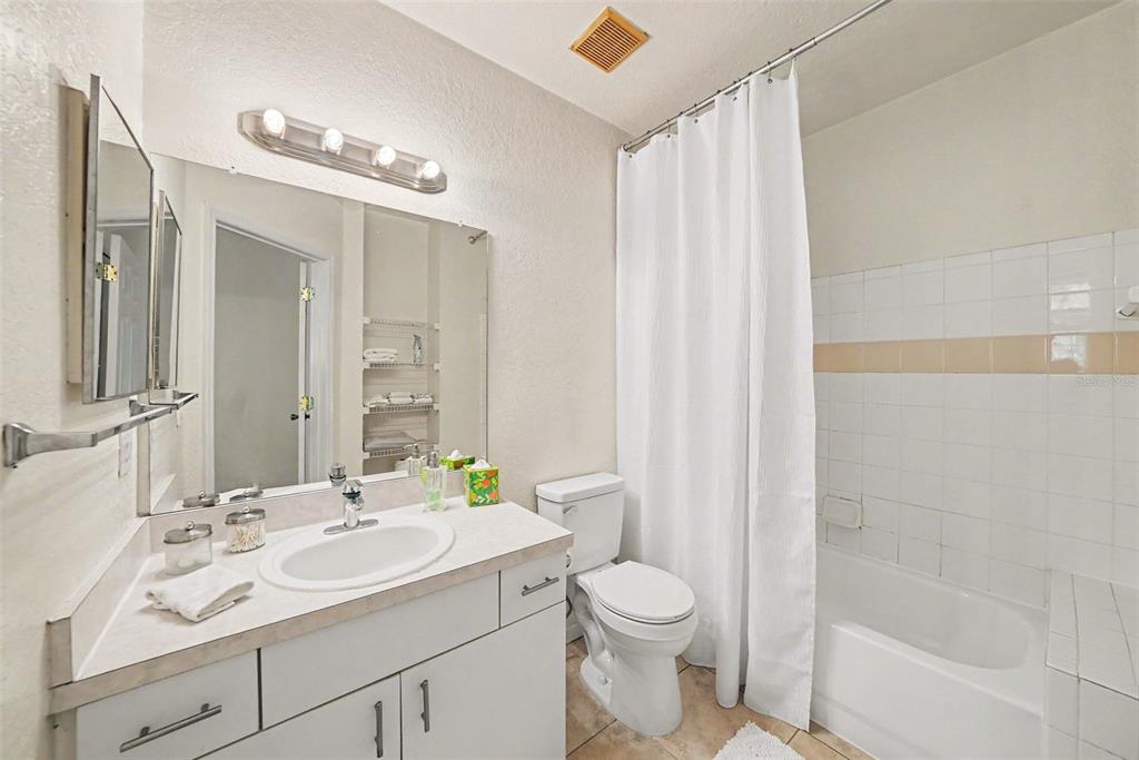 A bathroom features a white vanity, a large mirror, a toilet, and a shower-tub combination — 17108 CARRINGTON PARK DR UNIT 722, TAMPA, FL