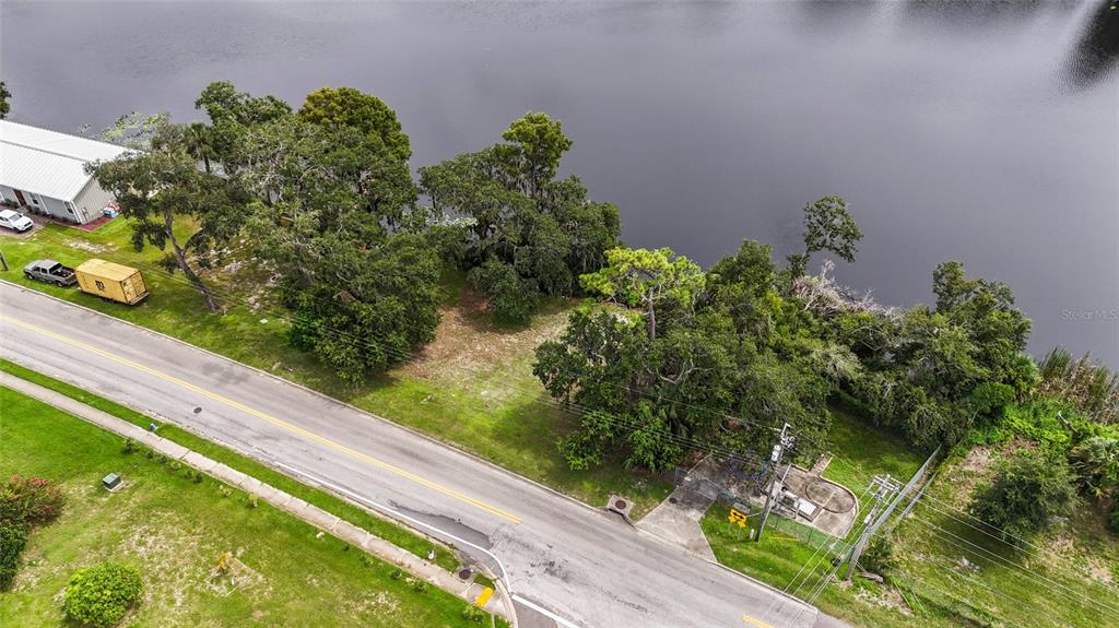 An aerial view shows a vacant lot situated between a road and a lake — 0 RIVERHILLS DRIVE, TEMPLE TERRACE, FL