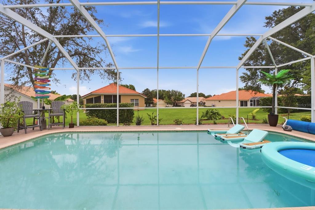A swimming pool with lounge chairs sits inside a screened-in lanai overlooking a grassy yard — 1096 W DIAMOND SHORE LOOP, HERNANDO, FL