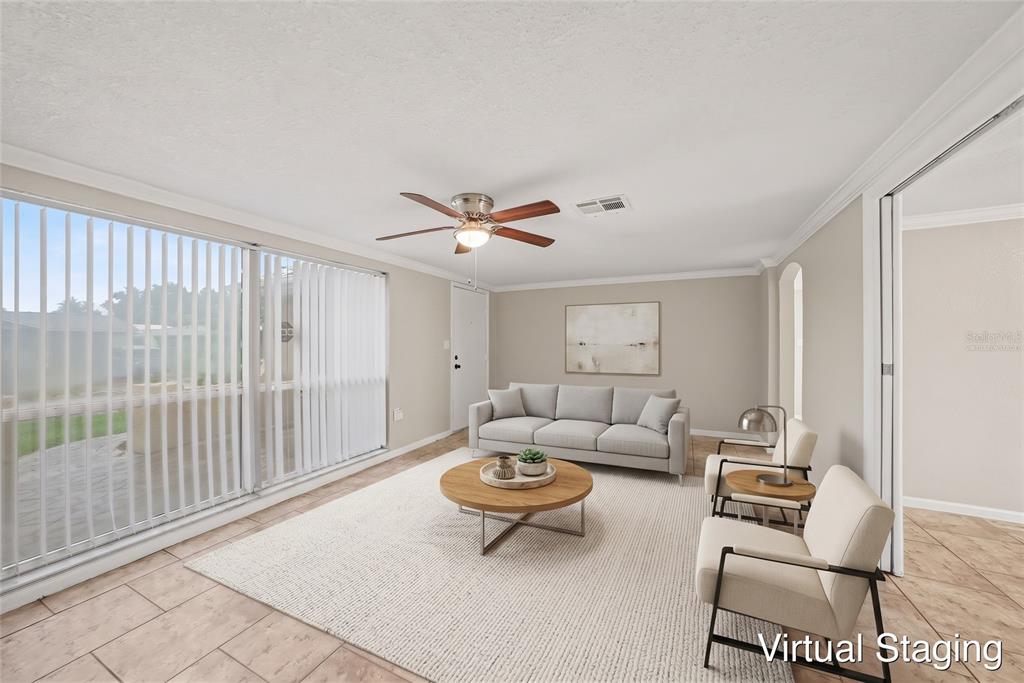 An empty room with tan tile flooring, a ceiling fan, and large vertical window blinds — 9135 HUNT CLUB LANE, PORT RICHEY, FL