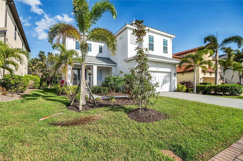 A two-story white house with a paved driveway, palm trees, and a green lawn — 5215 TITLE ROW DRIVE, BRADENTON, FL