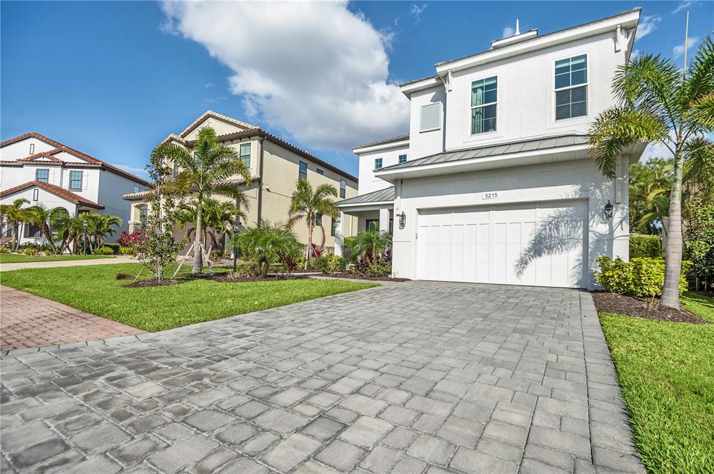 A white two-story house with a paver driveway and palm trees in the front yard — 5215 TITLE ROW DRIVE, BRADENTON, FL