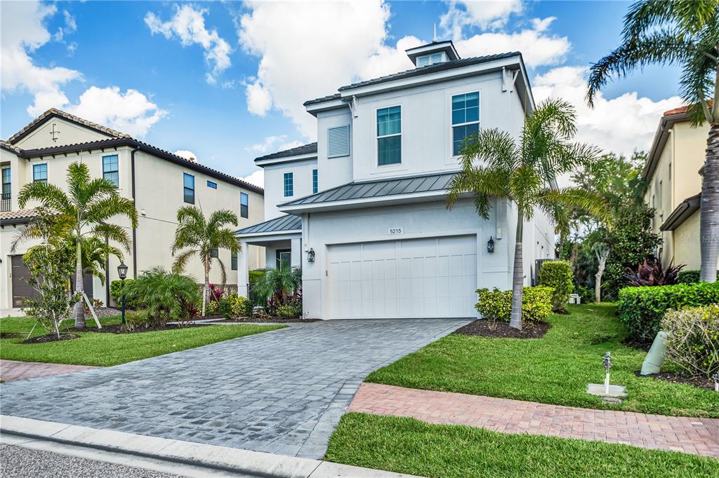 A two-story house with a white exterior, a two-car garage, and palm trees in front — 5215 TITLE ROW DRIVE, BRADENTON, FL