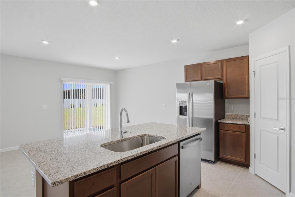 A kitchen with a granite-topped island, stainless steel appliances, and wood cabinets — 724 CANTABERRY DRIVE, DUNDEE, FL