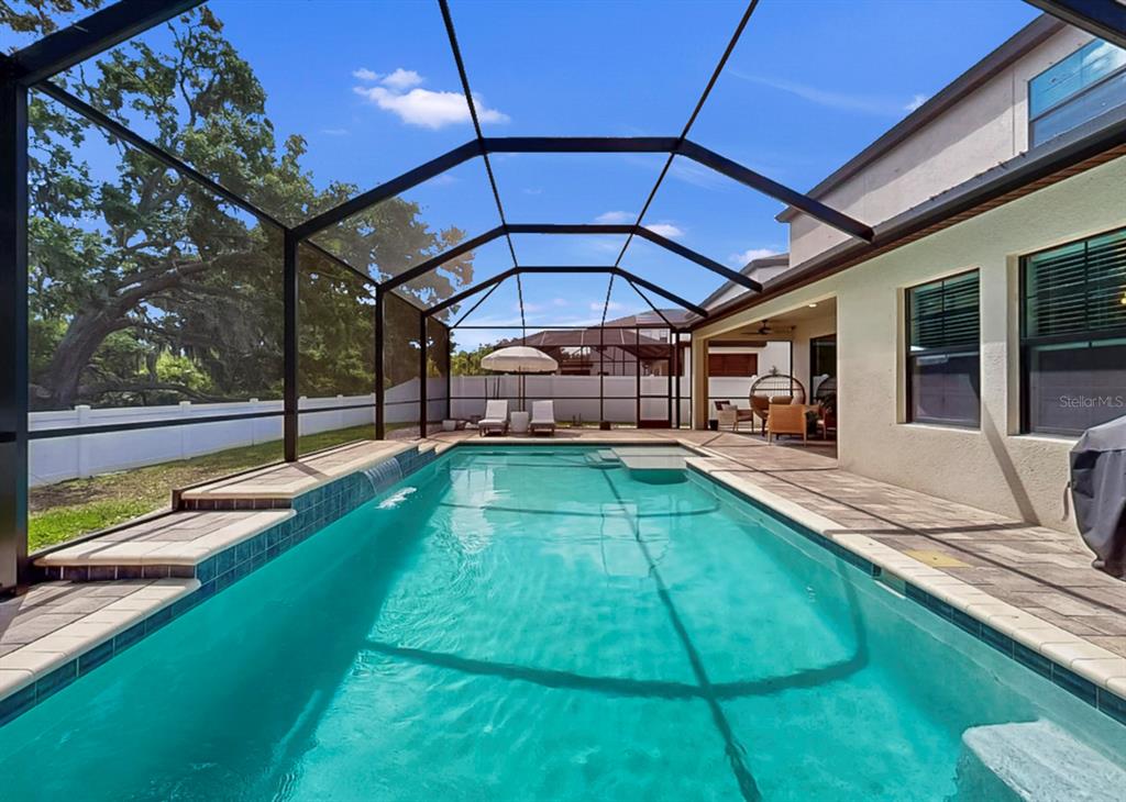 A rectangular swimming pool with a waterfall feature is enclosed by a screened lanai — 13036 PENNYBROOK DRIVE, RIVERVIEW, FL