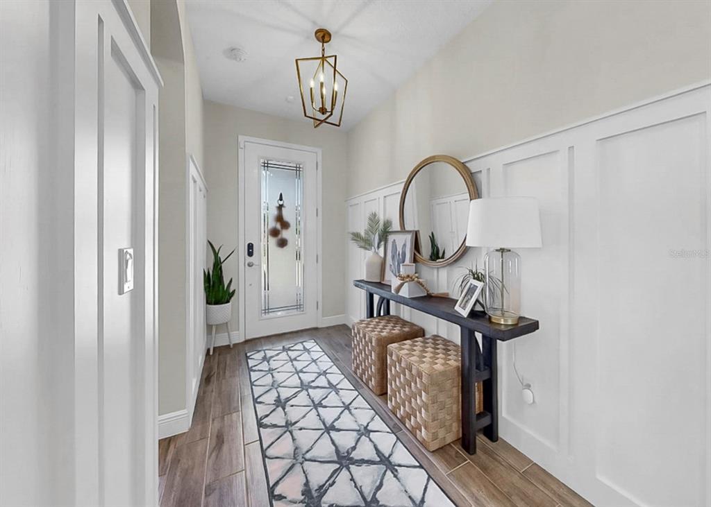 A bright entryway features a geometric pendant light, a console table with stools, and wainscoting — 13036 PENNYBROOK DRIVE, RIVERVIEW, FL