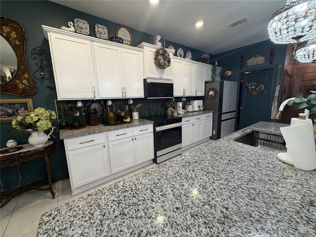 A kitchen features white cabinets, granite countertops, dark blue walls, and a large center island — 3795 SAGEFIELD DRIVE, HARMONY, FL