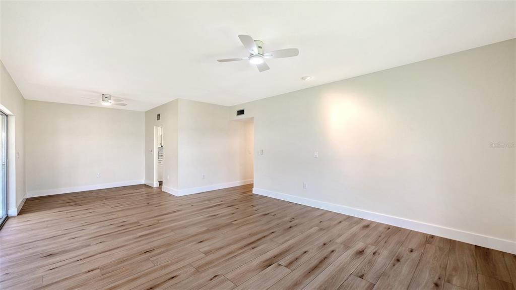 A bright living and dining area features light wood flooring, a sectional sofa, and sliding doors — 5911 TIDEWOOD AVENUE UNIT 3, SARASOTA, FL
