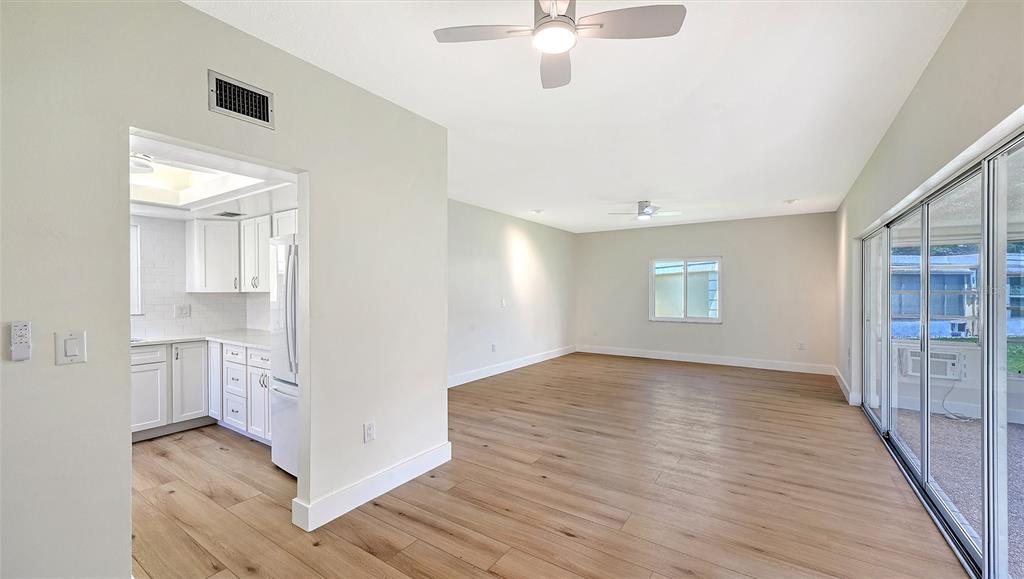 An empty room with light wood-look flooring, white walls, and two ceiling fans — 5911 TIDEWOOD AVENUE UNIT 3, SARASOTA, FL