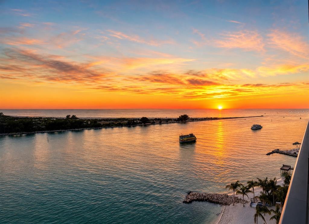 An elevated view of a sunset over a coastal inlet with boats and a sandy beach — 691 S GULFVIEW BOULEVARD UNIT 711, CLEARWATER, FL
