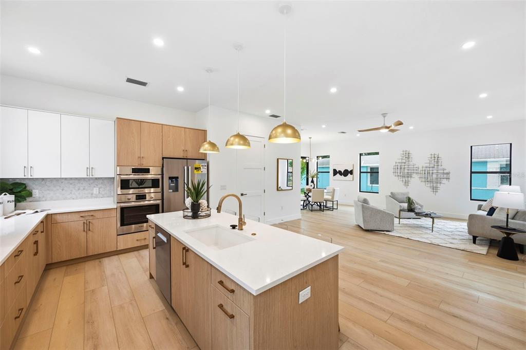A modern kitchen with light wood cabinets and a white island opens into a living area — 6325 11TH AVENUE S, GULFPORT, FL