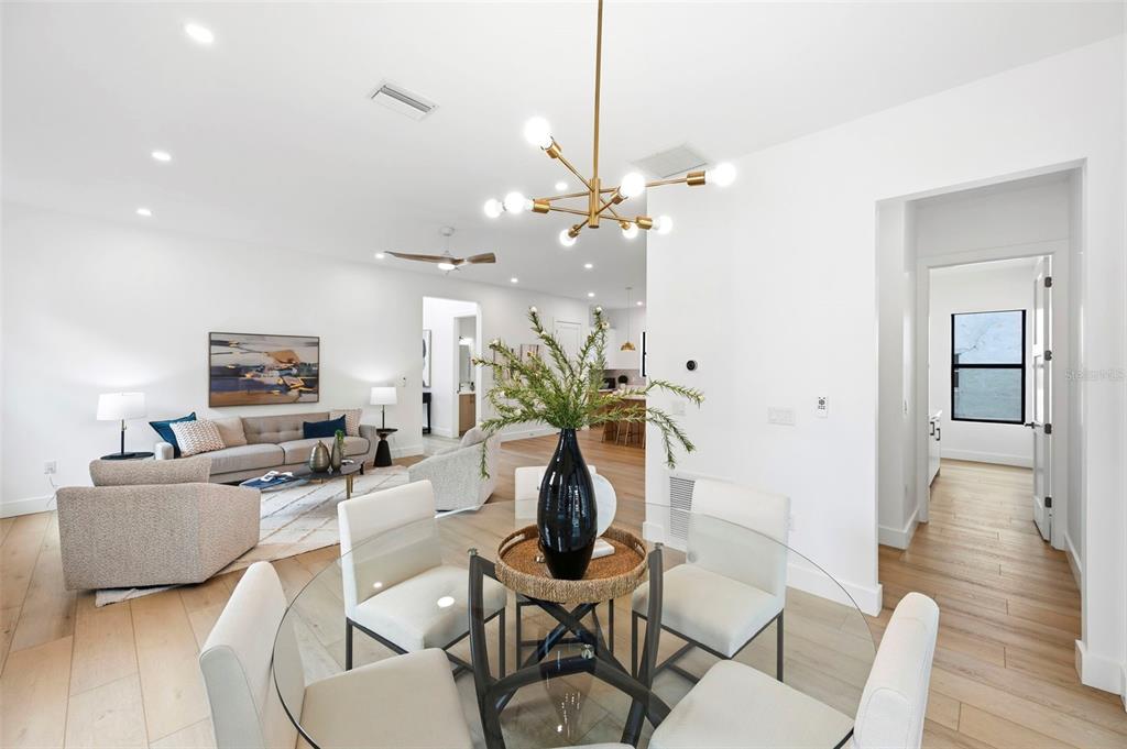 A dining area with a glass table and chandelier opens into a bright living room — 6325 11TH AVENUE S, GULFPORT, FL