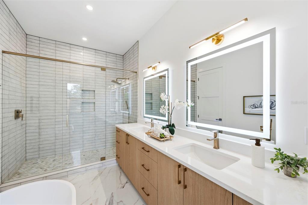 A modern bathroom features a double vanity, a glass-enclosed shower, and marble-look tile flooring — 6325 11TH AVENUE S, GULFPORT, FL