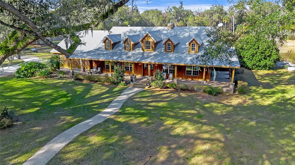 An aerial view of a rustic wooden house with a metal roof and five dormer windows — 27737 COUNTY ROAD 44A, EUSTIS, FL