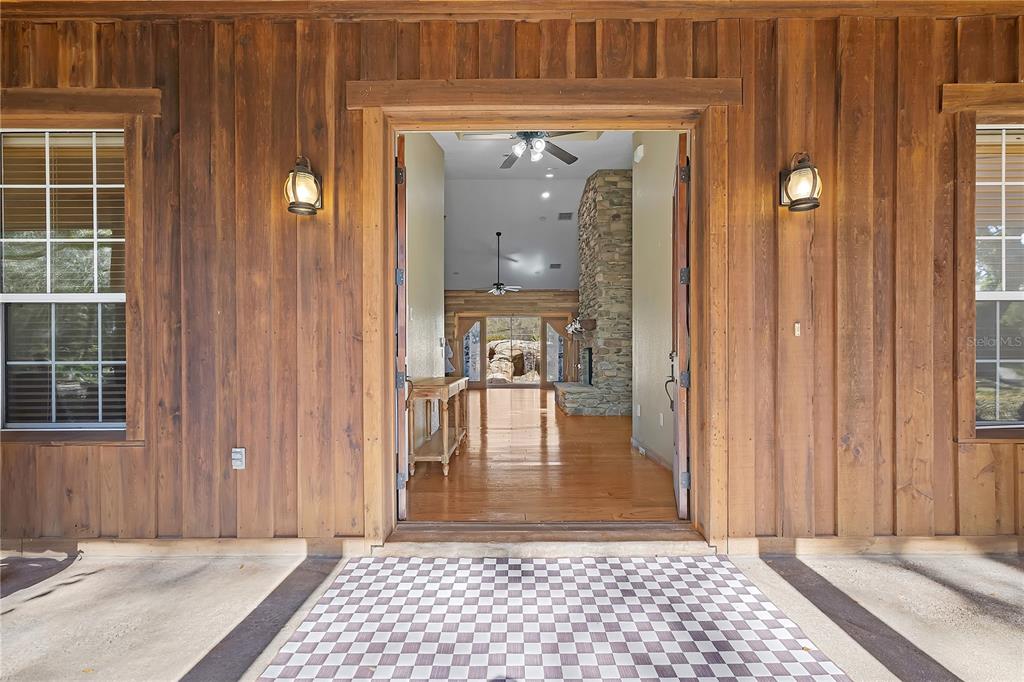 A wooden exterior entrance leads into a home with a stone fireplace and hardwood floors — 27737 COUNTY ROAD 44A, EUSTIS, FL