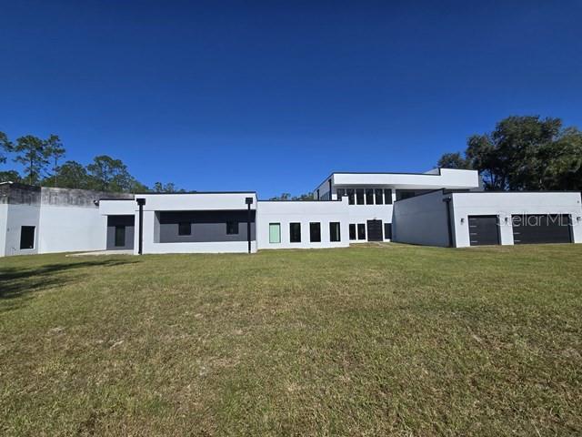 A modern, multi-level white house with flat roofs sits on a large, grassy lot — 2518 SUNSET LANE, LUTZ, FL