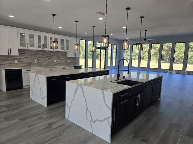 A modern kitchen features two large islands with white marble-patterned countertops and dark cabinetry — 2518 SUNSET LANE, LUTZ, FL