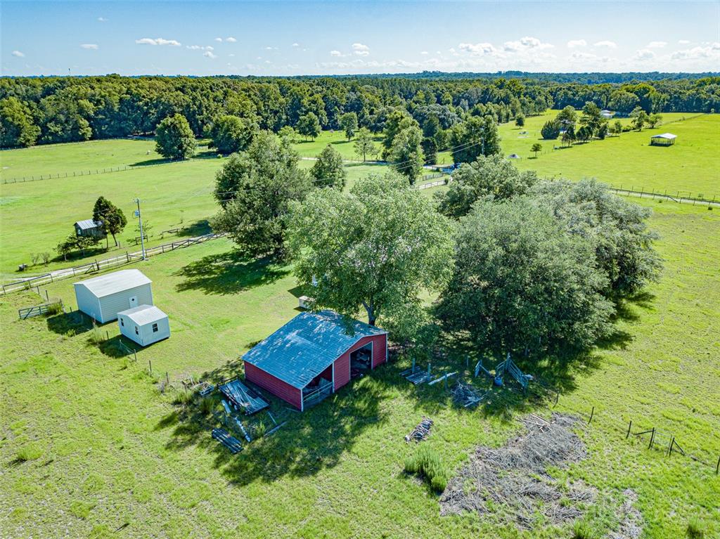 An aerial view shows a red barn, two small sheds, and trees on a grassy lot — 21528 NW 209TH TERRACE, HIGH SPRINGS, FL