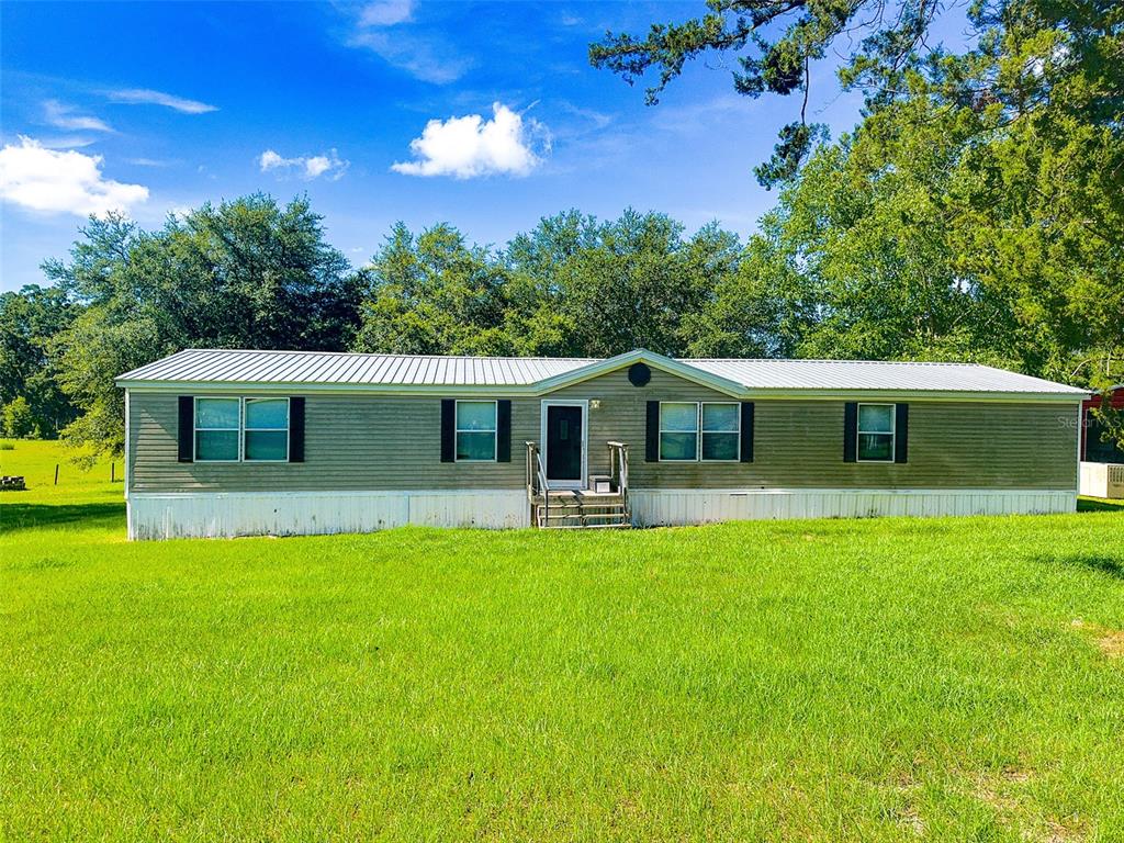 A single-story manufactured home with light siding and a metal roof sits on a lawn — 21528 NW 209TH TERRACE, HIGH SPRINGS, FL