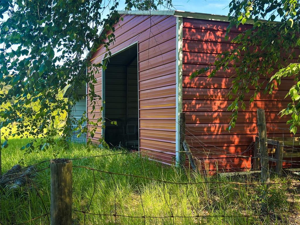 A red metal storage shed stands in a grassy field behind a wire fence — 21528 NW 209TH TERRACE, HIGH SPRINGS, FL
