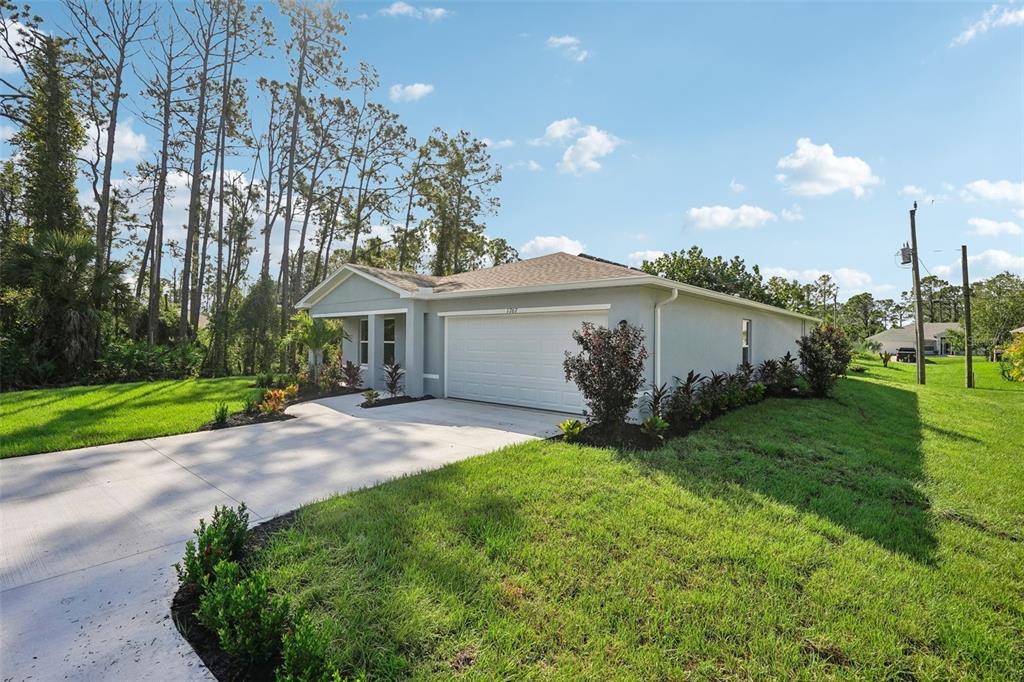 A light-colored single-story house with a two-car garage and a concrete driveway — 472 OAK CANOPY CIRCLE, AVON PARK, FL