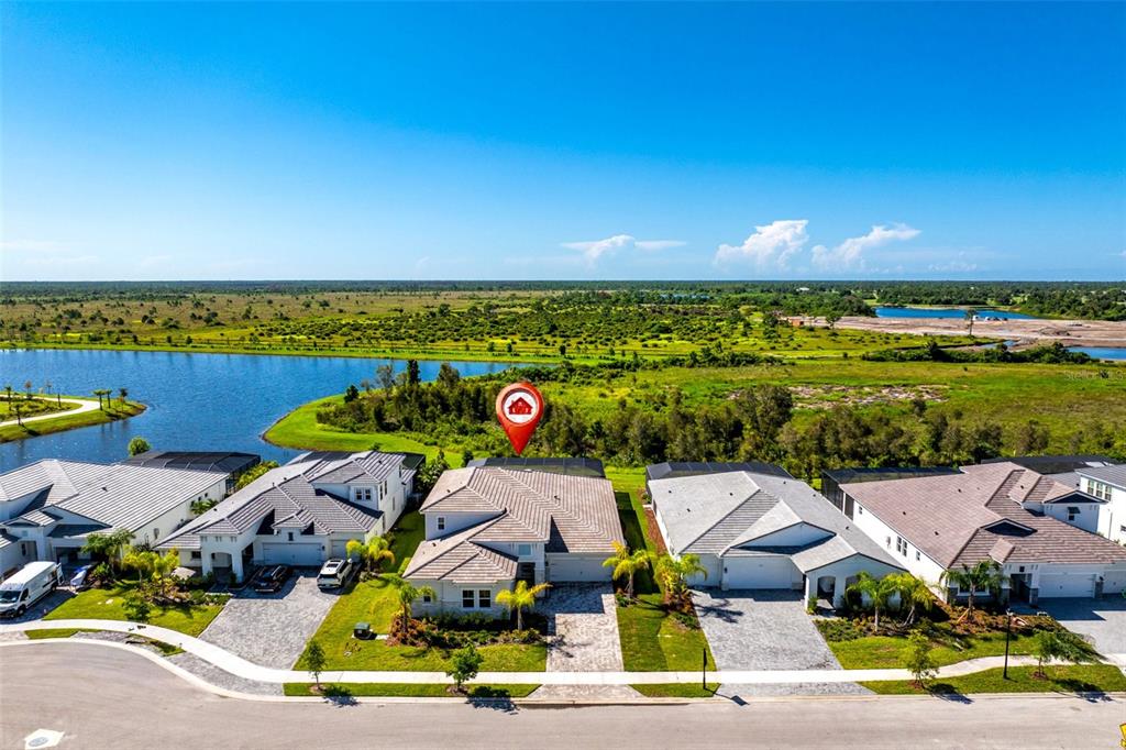 An aerial view shows a suburban house with a paved driveway facing a lake — 11225 BLISSBY STREET, VENICE, FL