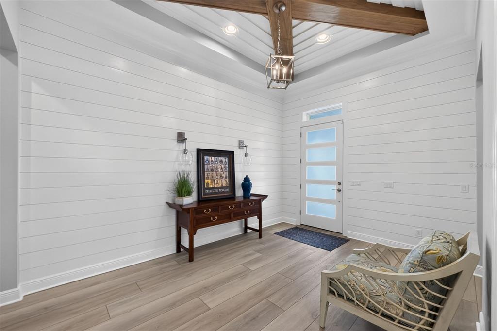 A bright entryway features white shiplap walls, wood-look flooring, a tray ceiling, and a wooden console — 11225 BLISSBY STREET, VENICE, FL