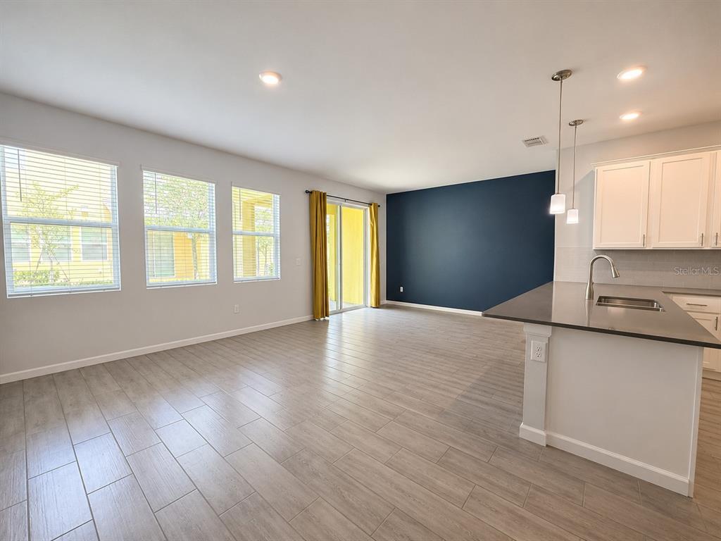 An open-concept living area features light wood-look tile floors, a dark blue accent wall, and kitchen — 9317 TECUMSEH DRIVE, ORLANDO, FL
