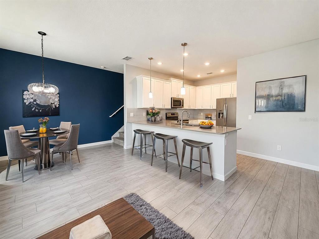 An open-concept kitchen and dining area features white cabinets, a breakfast bar, and navy walls — 9317 TECUMSEH DRIVE, ORLANDO, FL