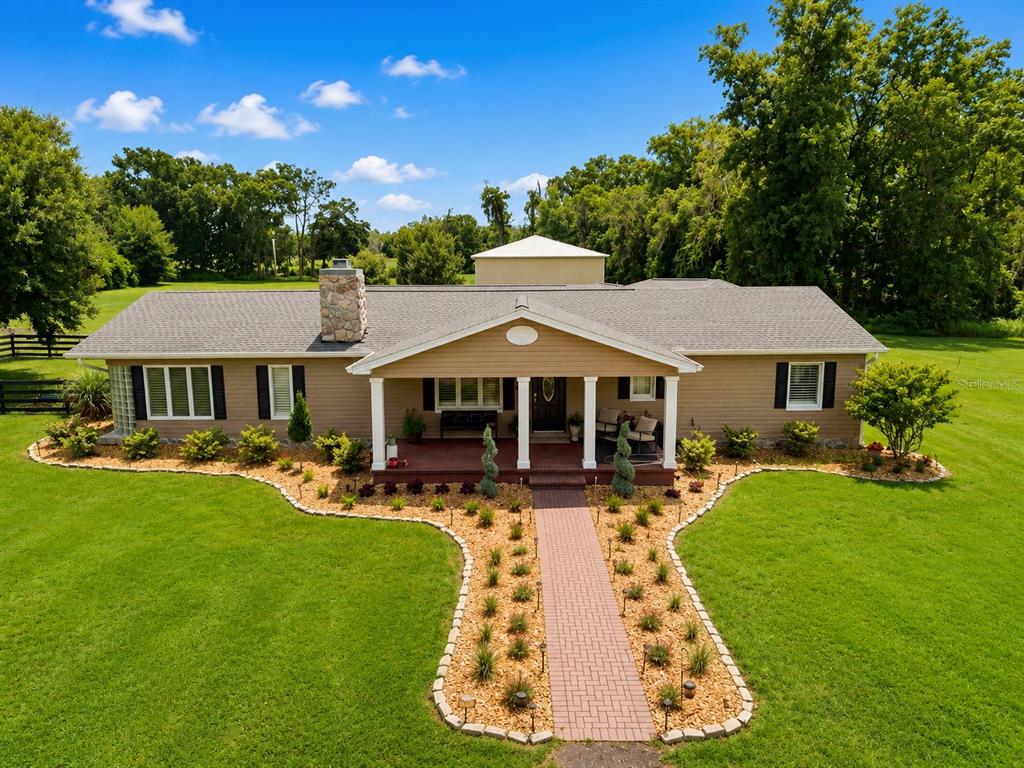 An aerial view of a single-story tan house with a stone chimney and front porch — 23458 CROOM ROAD, BROOKSVILLE, FL