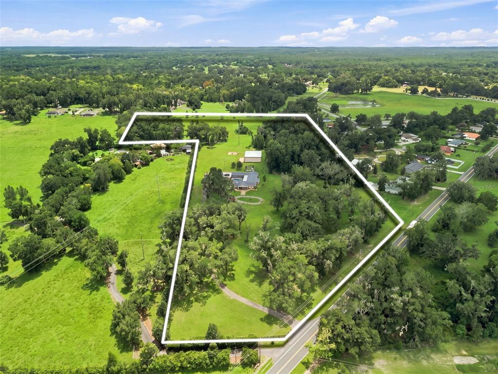 An aerial view shows a house and outbuildings on a large, tree-filled rural property — 23458 CROOM ROAD, BROOKSVILLE, FL