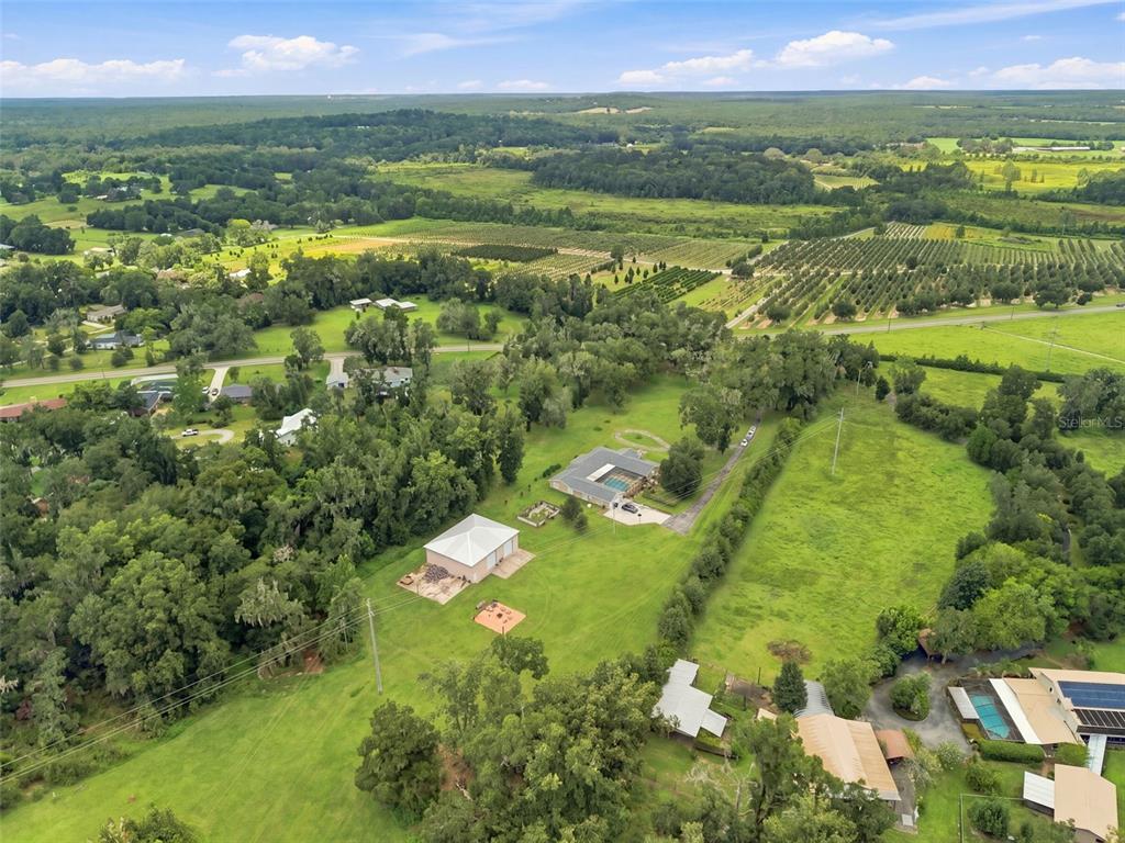 An aerial view shows a rural property with a house, pool, and detached garage — 23458 CROOM ROAD, BROOKSVILLE, FL