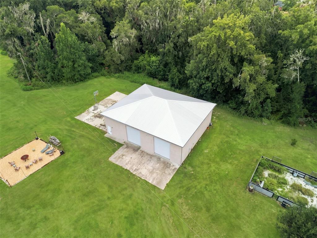 An aerial view shows a detached garage with a metal roof, concrete pads, and surrounding yard — 23458 CROOM ROAD, BROOKSVILLE, FL